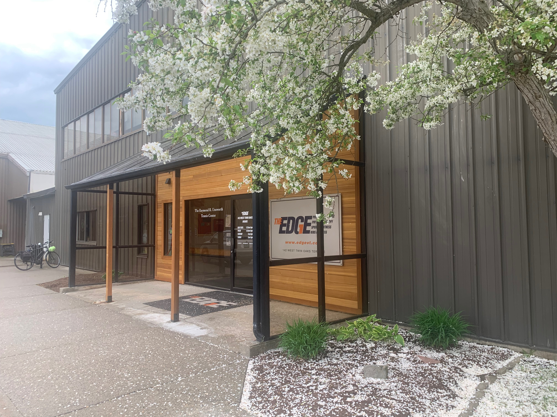 Exterior entrance canopy with cedar cladding, dark metal siding and a covered walkway at a South Burlington, Vermont fitness facility.